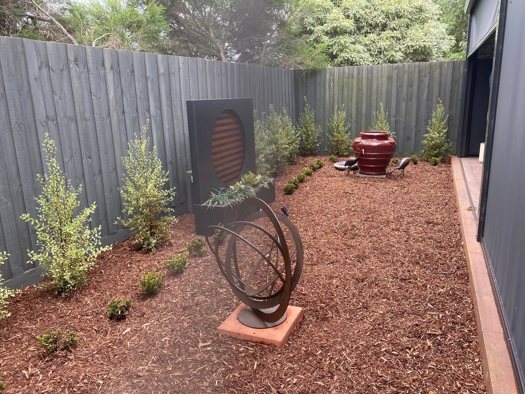 Fresh mulch and young plants arranged around garden sculptures